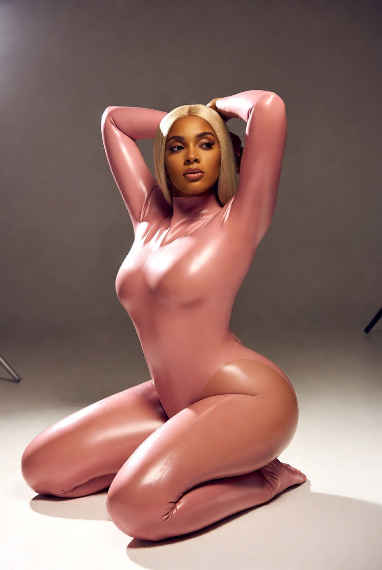 Person wearing a pink latex outfit posing against a neutral background