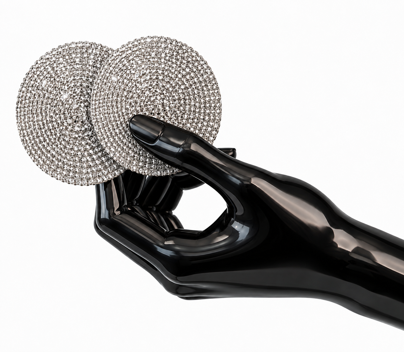A glossy black sculptural hand holding two round silver-discs densely covered in sparkling clear rhinestones, photographed on a clean white background.